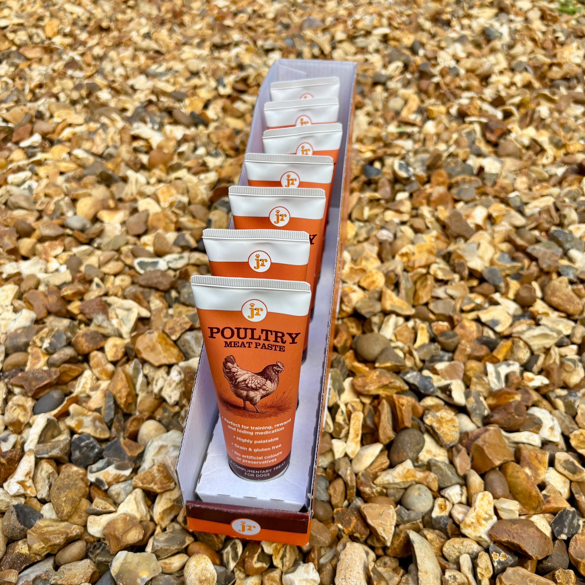 Row of poultry meat paste tubes in a box on a gravel background