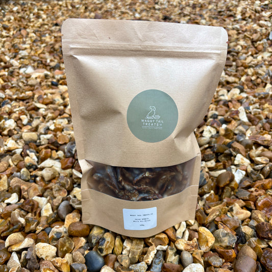 Kraft paper bag with a green label on a gravel background showing sprats a natural dog treat