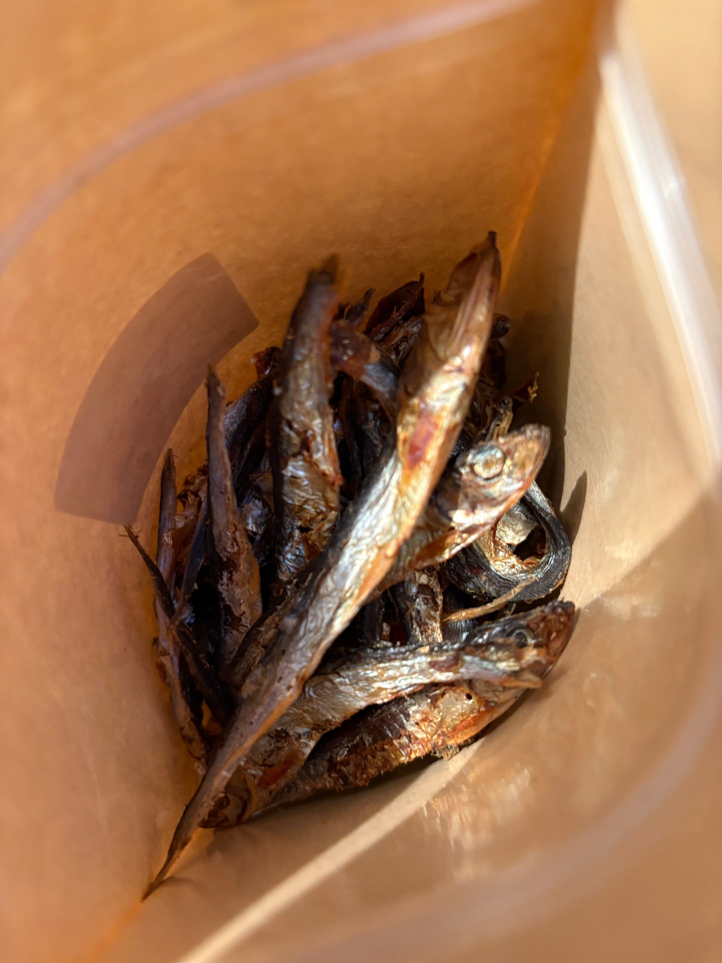 Dried fish in a clear plastic bag with a beige background