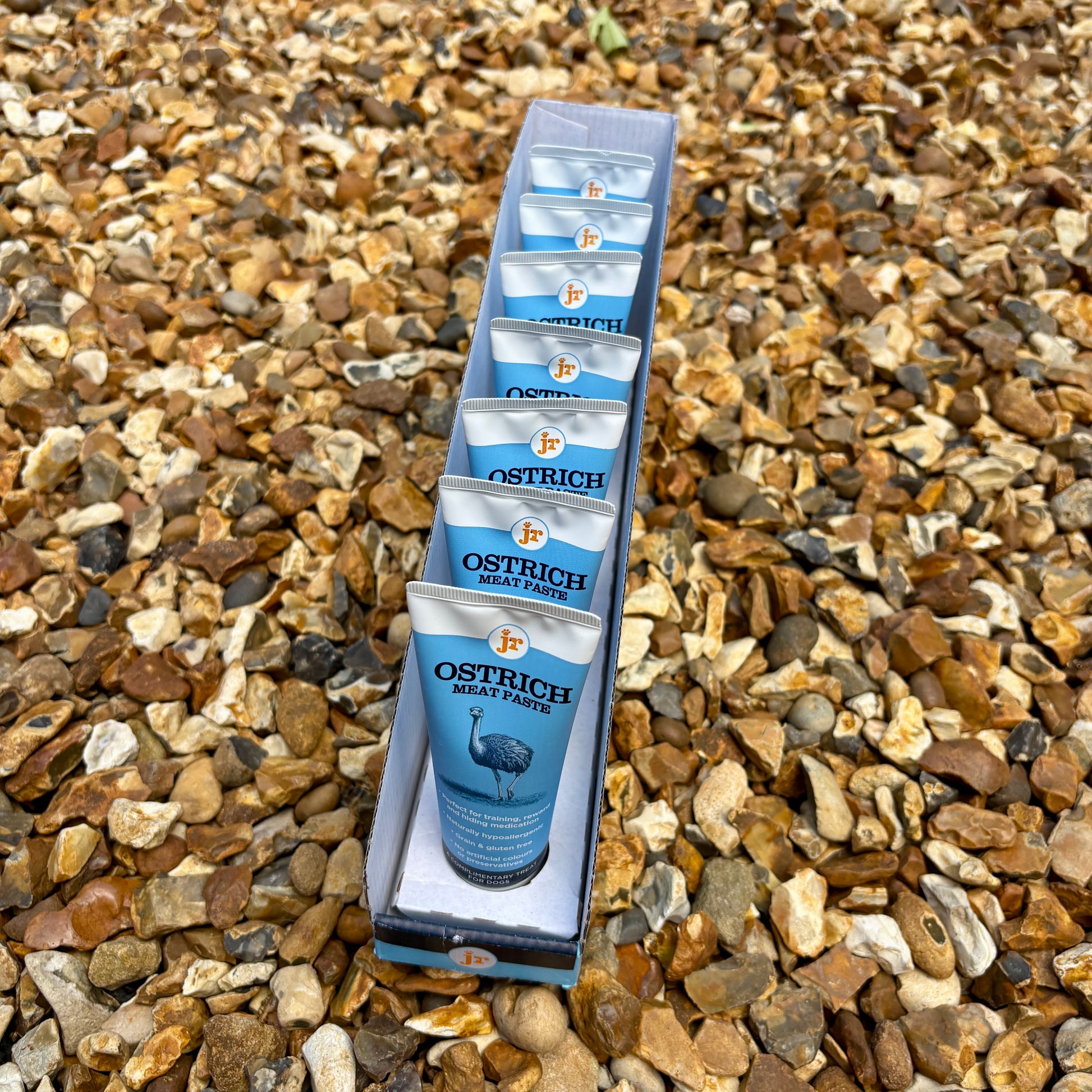 Ostrich meat packets in a box on a gravel surface