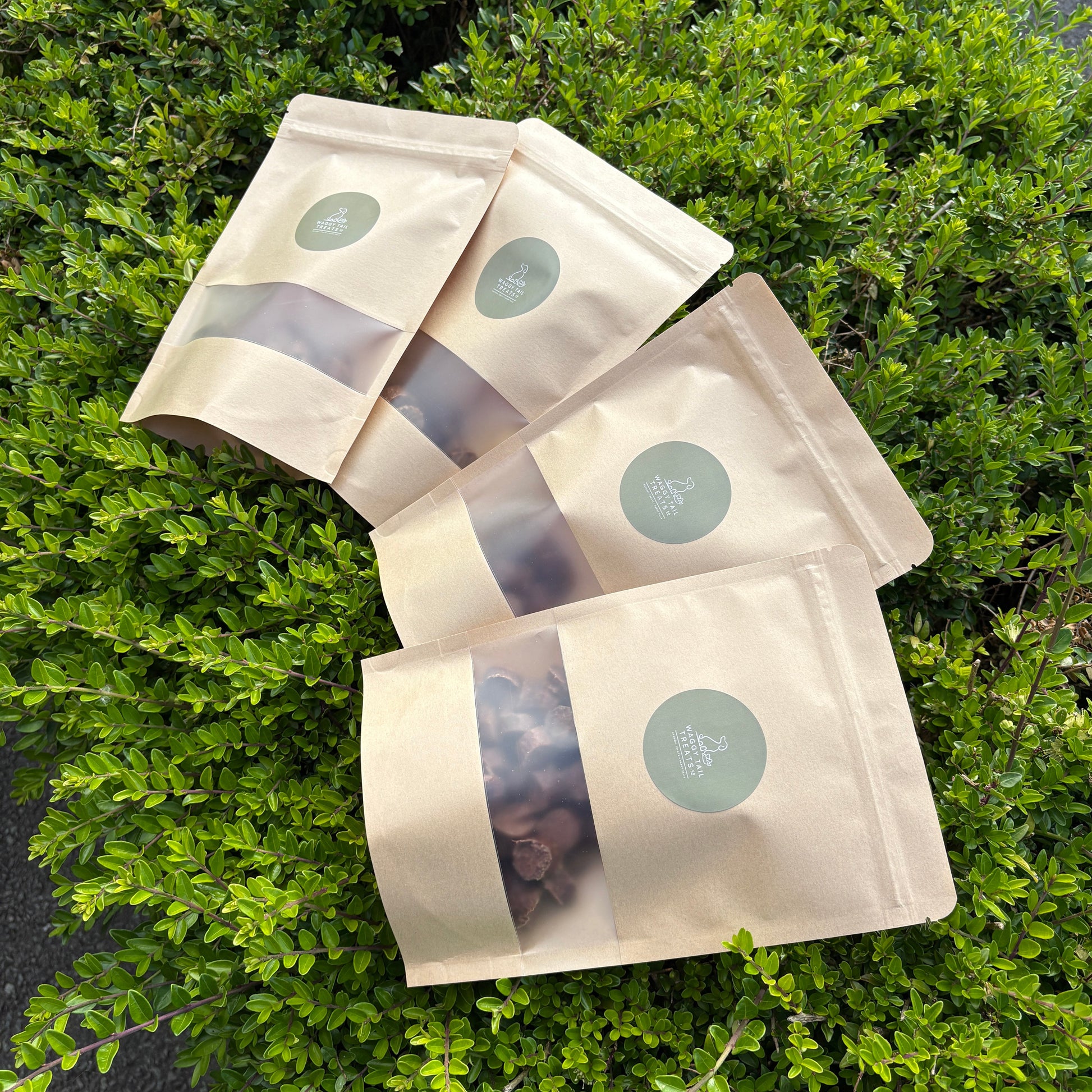 Three beige product packages with green labels on a green leafy background