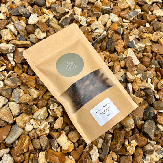 Kraft paper package with a clear window showing natural dog treats chicken hearts on a bed of small stones